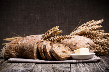 Tasty bread with wheat on wooden background.