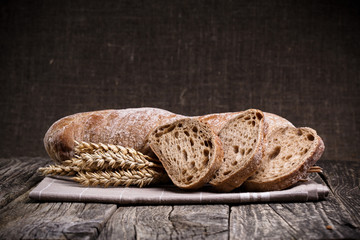 Tasty bread with wheat on wooden background.