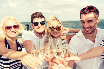 smiling friends with glasses of champagne on yacht