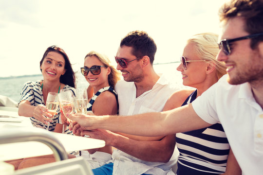 smiling friends with glasses of champagne on yacht
