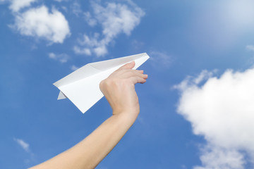 Paper plane in hand against the sky