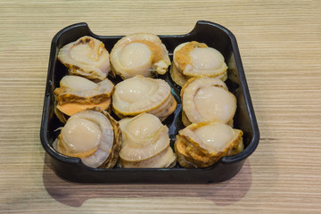 Nine Scallops in a black food tray.