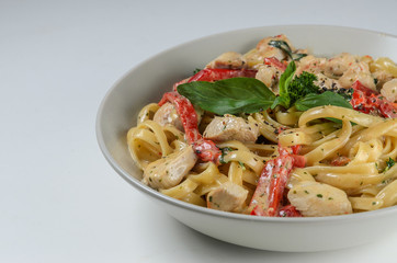 Bowl of pasta with chicken and capcicum served with fresh basil