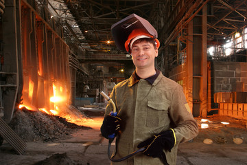 Portrait of a happy male welder standing against the foundry
