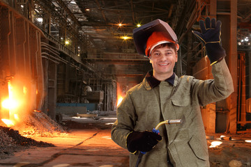 Portrait of a happy male welder standing against the foundry