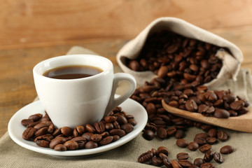 Cup of coffee with beans on rustic wooden background