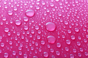 Water drops on glass on pink background