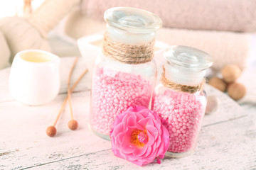 Glass bottles with color spa sea salt on wooden table, closeup