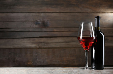 Wine bottle with glass on wooden background