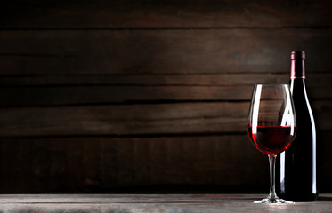 Wine bottle with glass on wooden background