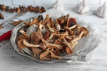 Dried mushrooms in plate on wooden table, closeup