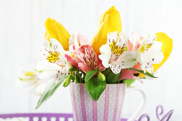 Beautiful flowers in cup, on wooden background