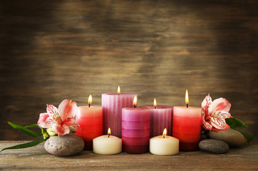 Obraz na płótnie Canvas Candles with flowers on wooden background