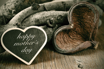 happy mothers day in a heart-shaped chalkboard on a rustic backg