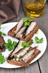 Appetizer bread with sprats on white plate