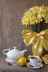 A cup of tea and a bouquet of daffodils.