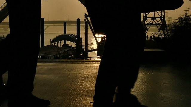 Slow motion sunset silhouette of people on the boardwalk.