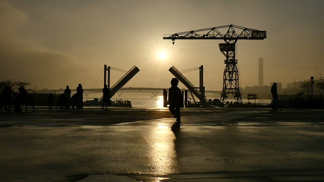 Slow motion sunset silhouette of people on the boardwalk.