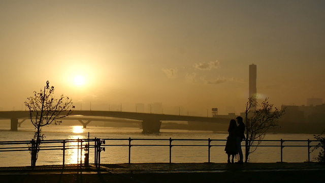 Slow motion sunset silhouette of people on the boardwalk.