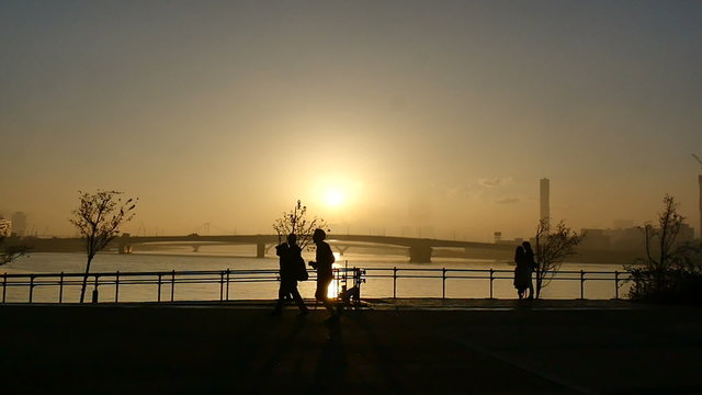 Slow motion sunset silhouette of people on the boardwalk.