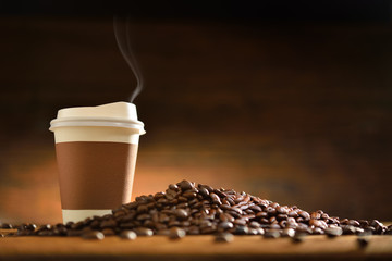 Paper cup of coffee  and coffee beans on old wooden background
