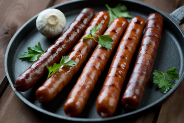 Grilled sausages with parsley and garlic in a frying pan