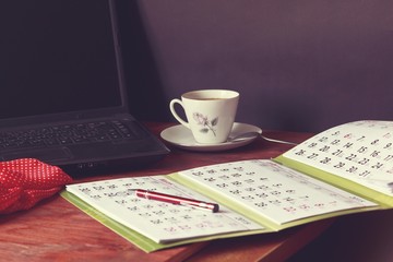 Vintage photo of workspace with calendar, laptop and other equipment