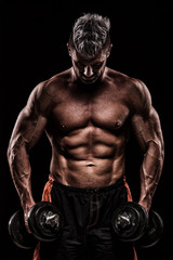Fototapeta na wymiar muscular young man lifting weights on dark background