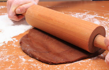 Hand with rolling pin kneading dough for cookies