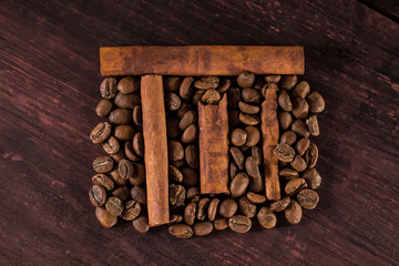 Roasted brown coffee beans with cinnamon sticks on wooden table
