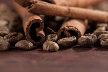 Roasted brown coffee beans with cinnamon sticks on wooden table