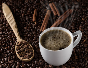 Cup French coffee with cinnamon sticks and background of beans