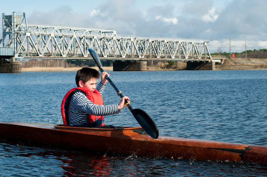 The boy rowing in a kayak on the river
