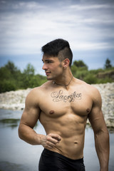Muscular shirtless young man in nature with plants, river