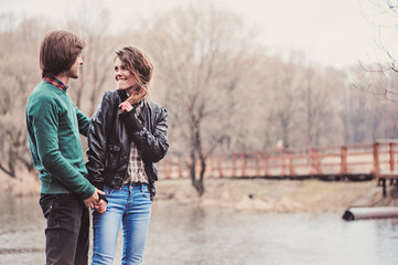 young happy loving couple on the walk in early spring riverside