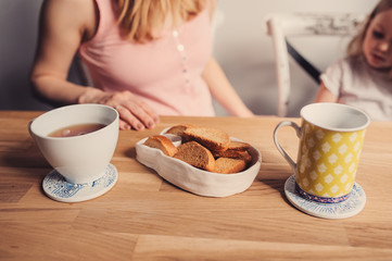 tea and cookies for breakfast with mother and baby on background