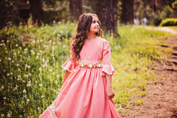 Fototapeta na wymiar happy child girl in fairytale princess dress dancing in forest