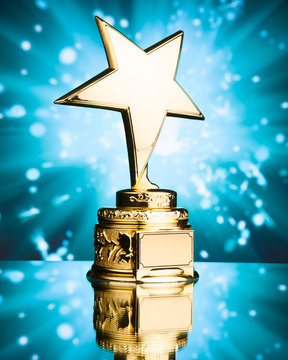 gold star trophy against blue sparks background