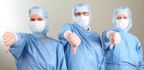 Drei Ärzte im OP oder Pharma mit Daumen nach unten