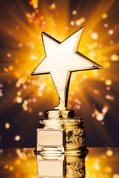 gold star trophy against shiny sparks background