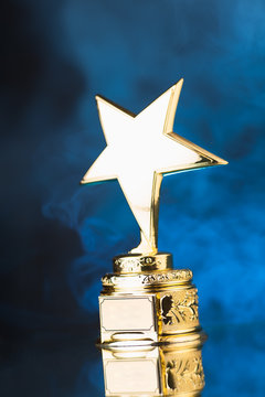 gold star trophy against blue smoke background