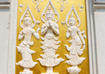 white asian angel sculpture on golden wall
