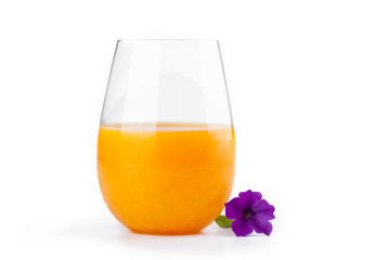 The glass of fresh orange juice and beautiful violet flower on w
