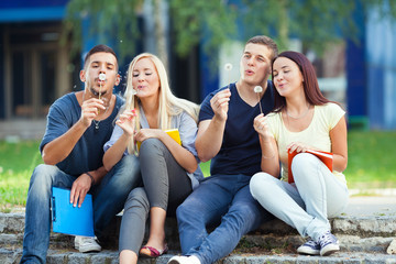 Four students blowing dandelions