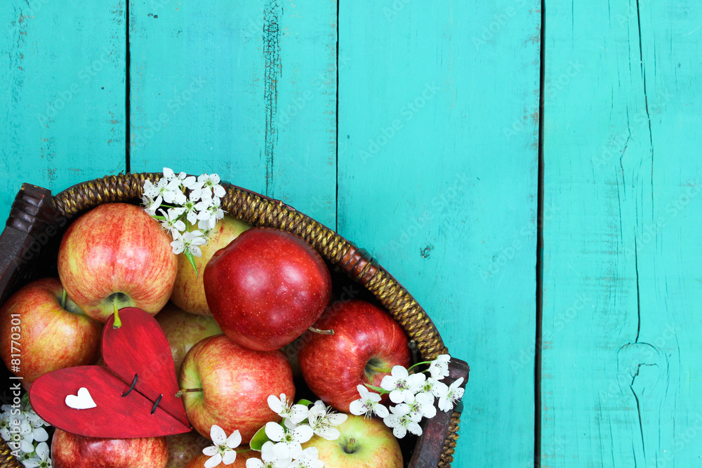 Wall mural basket of red apples and blossoms on blue wood background