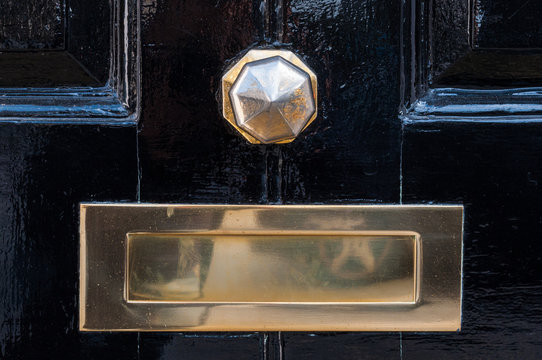 Metal mailbox and door knob on a black painted door