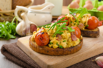 Scrambled eggs witch bacon, herbs and tomato
