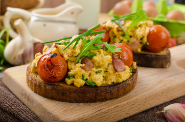 Scrambled eggs witch bacon, herbs and tomato