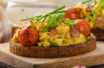 Scrambled eggs witch bacon, herbs and tomato