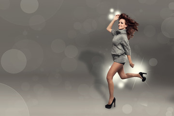 Fototapeta na wymiar Fashion photo of running brunette woman over sparkling grey back
